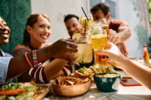 Close up of friends toasting with drinks while gathering in a restaurant.