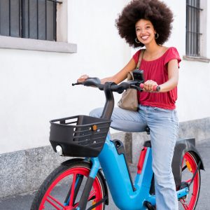 Happy black woman with electric bicycle standing on street