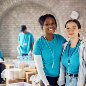 Young female volunteers working at donation center and looking at camera.