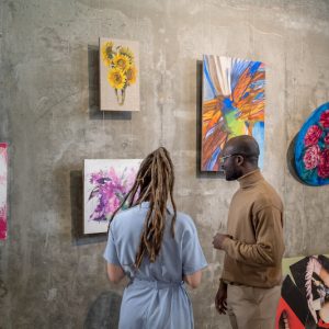 Young intercultural man and woman discussing one of paintings
